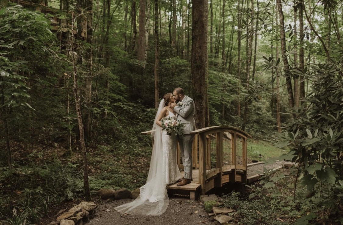 Wedding couple kissing on a private wooden bridge at Treehouse Grove